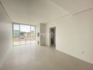 Ambiente interno de uma sala ampla com piso de cerâmica e grande janela.