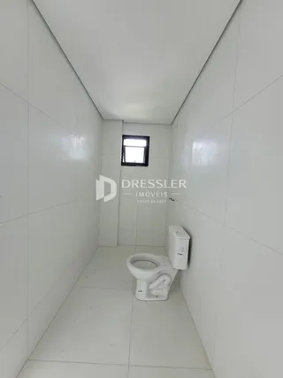 Corredor interno de uma residência com paredes brancas e piso claro.
