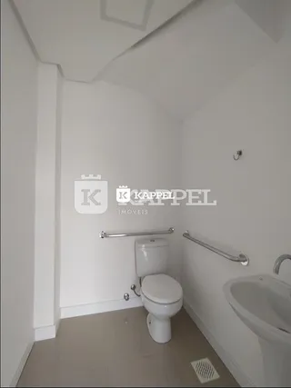 Foto interna de um banheiro com vaso sanitário e pia brancos.
