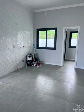 Hall de entrada com parede branca e piso de concreto polido.