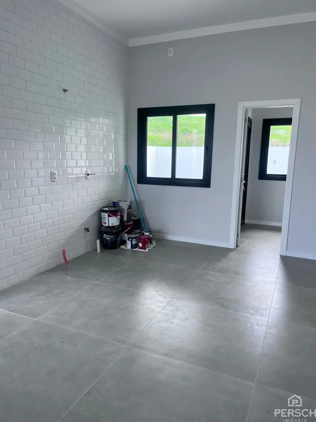 Hall de entrada com parede branca e piso de concreto polido.