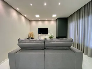 Sala de estar com sofá cinza e iluminação moderna.