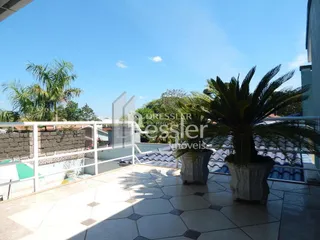 Vista de uma varanda externa com piso de cerâmica e vegetação.