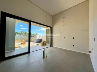 Vista interna de um ambiente com porta de vidro que dá para uma área externa em construção.