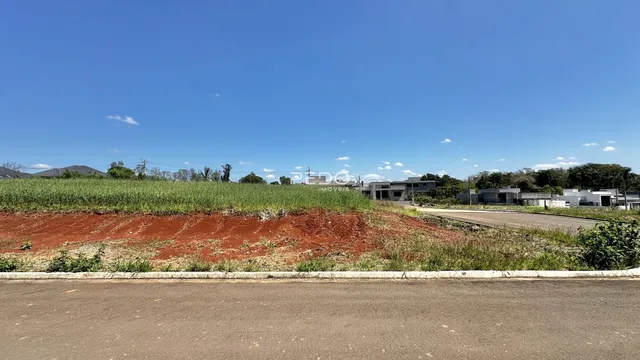 Paisagem de terra vermelha com vegetação ao lado de uma estrada.