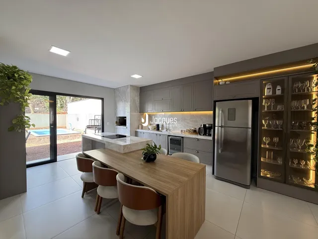 Vista da cozinha e sala de jantar com portas de vidro abrindo para o exterior.