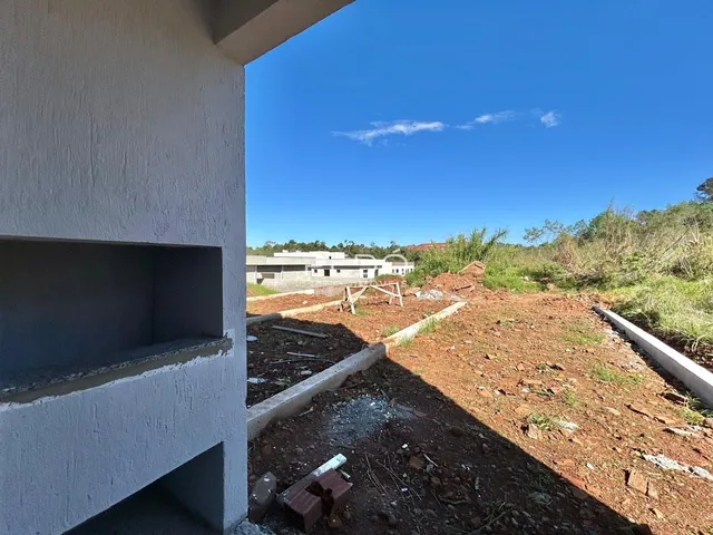 Vista externa de uma construção com terreno baldio ao fundo.