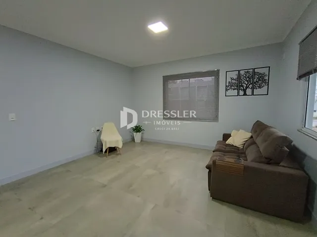 Sala de estar com piso de madeira clara e sofá no ambiente.