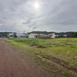 Vista de uma área de campo com estrada de terra sob um céu nublado.