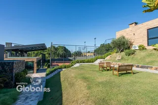 Jardim com bancos e cerca ao lado de uma residência moderna.