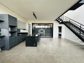 Vista da cozinha moderna com armários escuros e piso claro.
