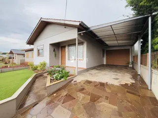 Vista externa de uma residência com área de lazer pavimentada e jardim.