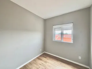 Uma sala de estar com paredes cinzas e piso de madeira clara.