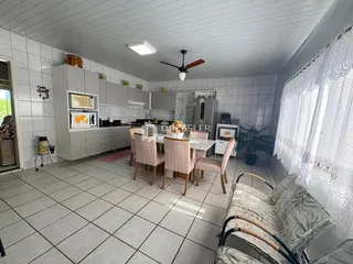 Interior de uma sala de estar e cozinha com área de jantar em um imóvel no Brasil.