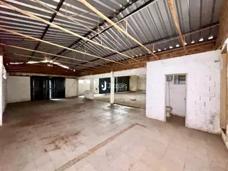 Espaço interno amplo com teto de estrutura metálica exposta e piso de cerâmica.