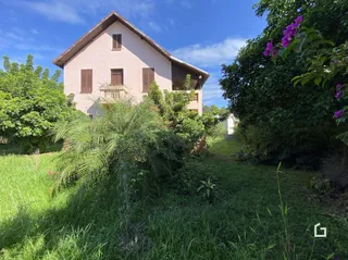 Fachada de uma residência em Lajeado, Brasil, com vegetação densa ao redor.