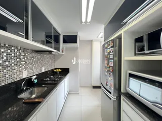 Vista da cozinha moderna com armários brancos e bancadas escuras.