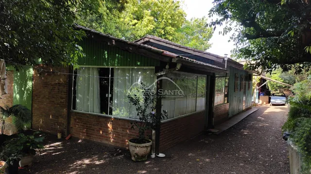 Vista externa de uma casa com paredes verdes e telhado de telhas em Lajeado.