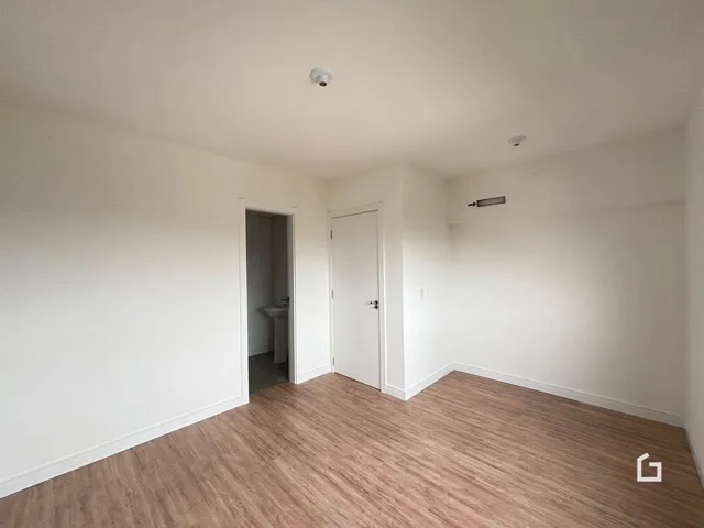 Ambiente interno com piso de madeira clara e paredes brancas.