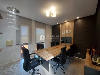 Interior de um escritório com mesa de madeira e cadeiras de escritório.