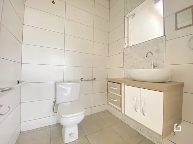 Foto de um banheiro com revestimento cerâmico branco.