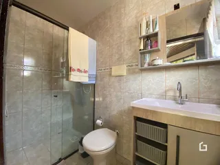 Foto de um banheiro com revestimento de cerâmica e box de vidro.