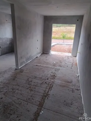 Foto de um cômodo interno em estado de obra com piso de concreto aparente.