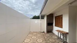 Área externa pavimentada com piso de cerâmica e parede de tijolos em uma residência.