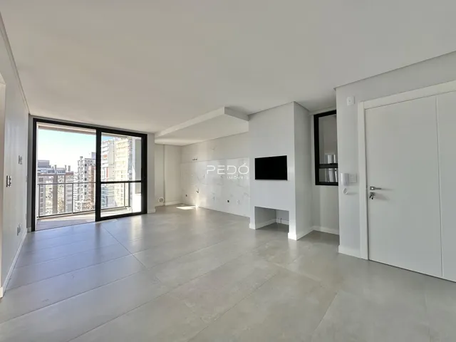 Sala de estar ampla com piso de concreto claro e porta de vidro.