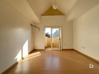 Interior de uma sala com piso de madeira e parede branca.