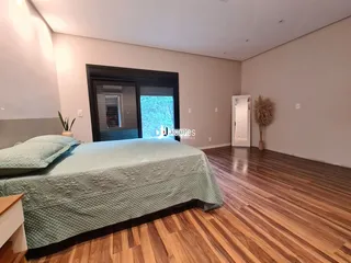 Quarto com cama e piso de madeira no interior da residência.