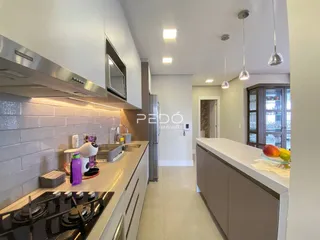 Vista da cozinha moderna com armários brancos e bancada clara.