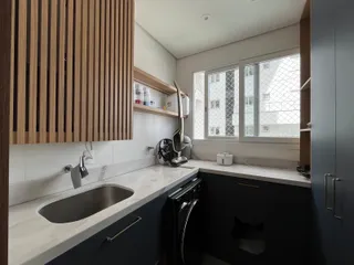 A cozinha moderna apresenta armários de madeira e bancadas claras.
