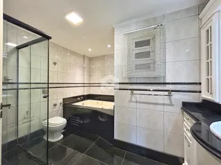 Banheiro com box de vidro e banheira em um imóvel.