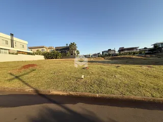 Vista da propriedade com área gramada e casas ao fundo.