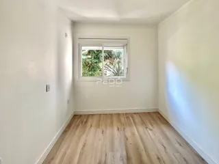Ambiente interno com piso de madeira clara e parede branca.