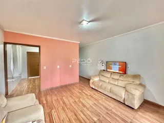 Sala de estar com piso de madeira e sofá bege.