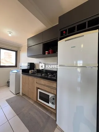 Foto interna de uma cozinha com armários escuros e eletrodomésticos brancos.