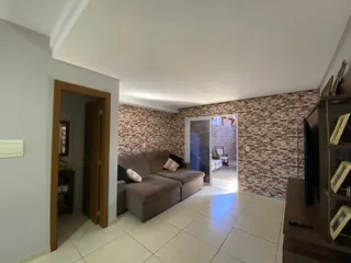 Sala de estar com sofá marrom e parede de tijolos aparentes.