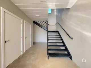 Hall de entrada com portas brancas e escada de ferro em um imóvel.