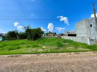Vista externa de uma propriedade com vegetação e construção em concreto no fundo.