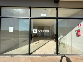 Foto da entrada de um imóvel com grandes portas de vidro e um espaço interno vazio.
