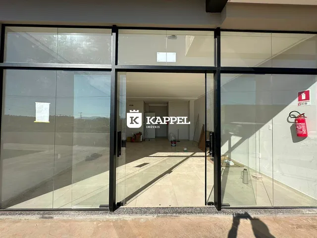 Foto da entrada de um imóvel com grandes portas de vidro e um espaço interno vazio.