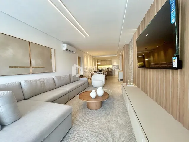 Sala de estar com sofá e televisão na parede de uma residência.