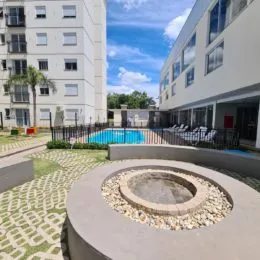 Foto de uma piscina azul em uma área externa com paisagismo.