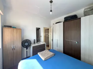 Quarto com armários de madeira e cama azul em um apartamento.