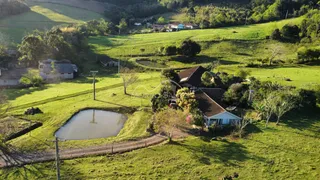 Vista aérea de uma propriedade rural com campos verdes e uma área de água.