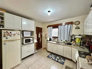 Foto interna de uma cozinha com armários brancos e piso de cerâmica.