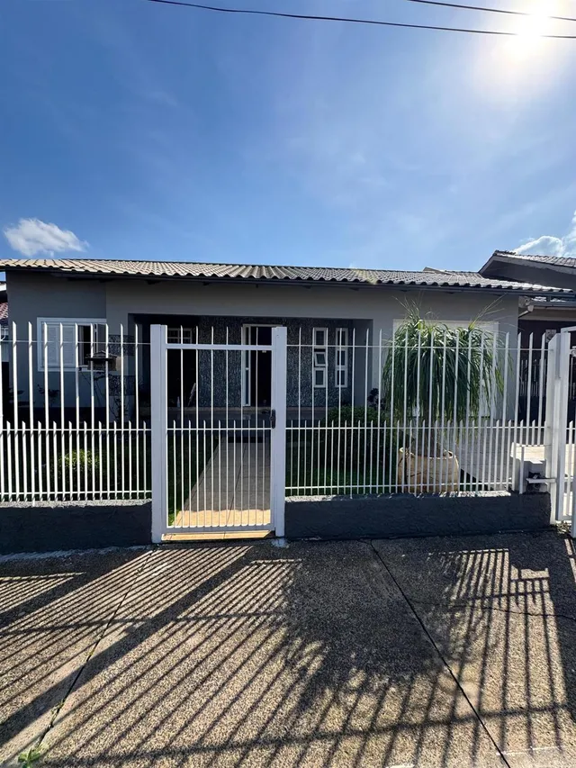Fachada da casa com cerca e portão branco na rua.