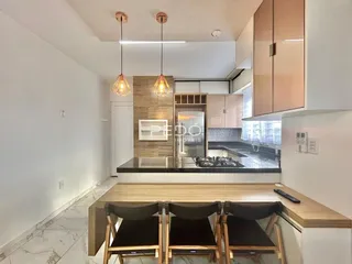 Vista da cozinha e sala de jantar com armários e iluminação moderna.